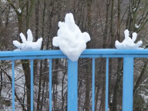 Schneepunk: ein Kopf mit Irokesenschnitt und zwei offene Hände aus Schnee auf einem Brückengländer = ein Schneepunk :)