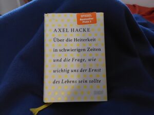 Das gelb gepunktete Cover von Axel Hackes Buch auf einer dunkelblauen Decke.