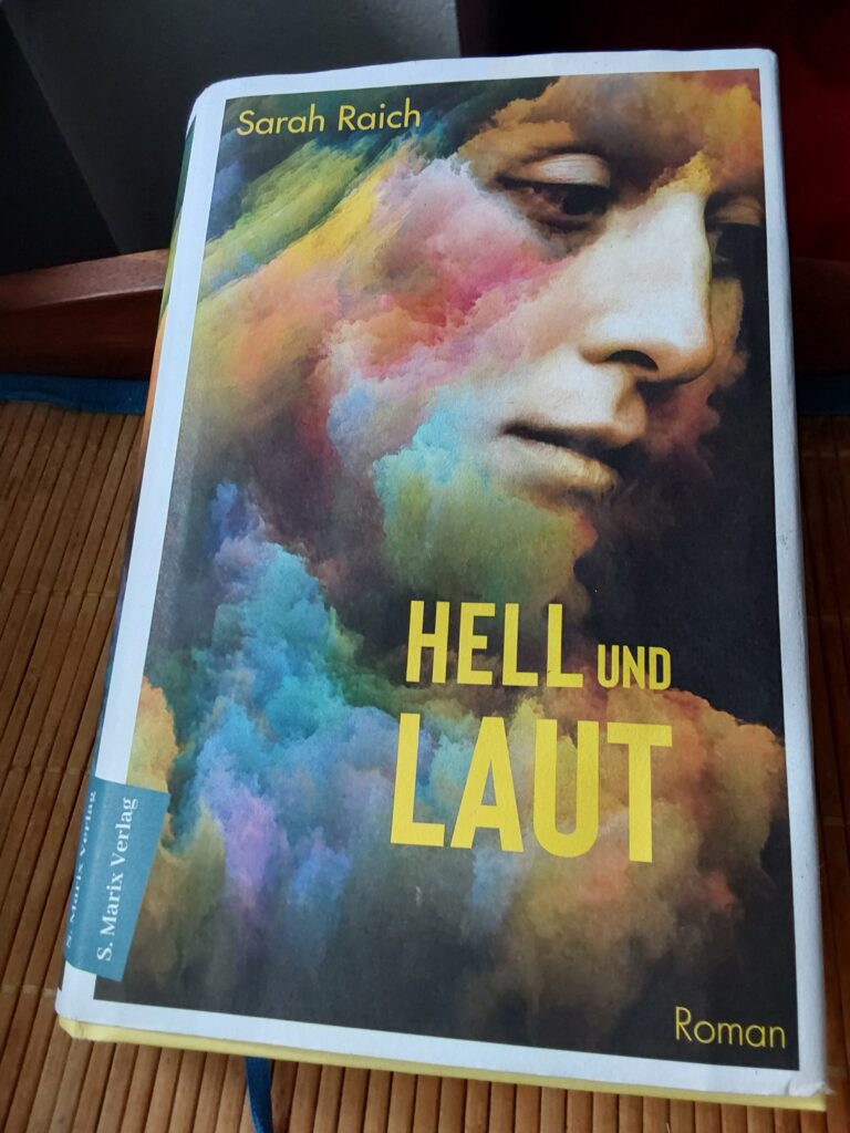 Das Cover des Romans "Hell und Laut" von Sarah Raich zeigt eine nachdenkliche, junge Frau, über deren Bild regenbogenfarbene Farbwolken liegen