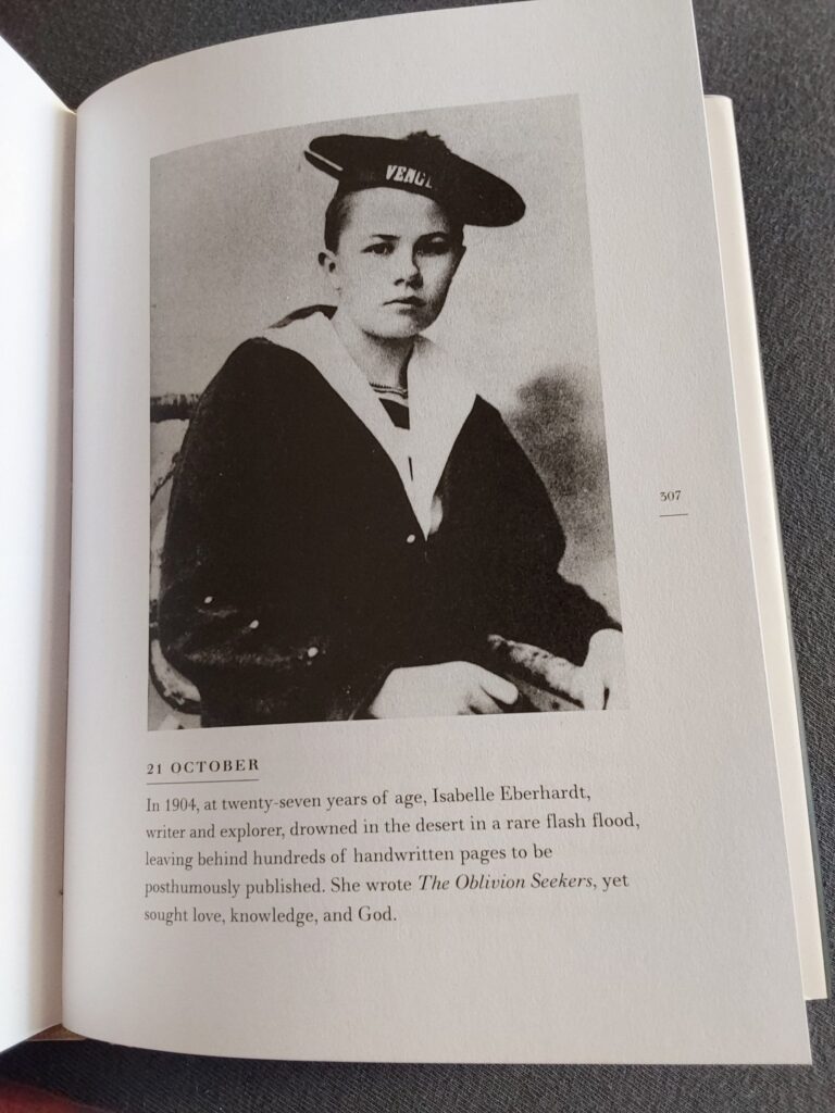 Ein Porträtfoto aus dem frühen 20. Jahrhundert zeigt Isabelle Eberhardt, eine junge Frau in einem Matrosenanzug, die mit ernstem Blick in die Kamera schaut.