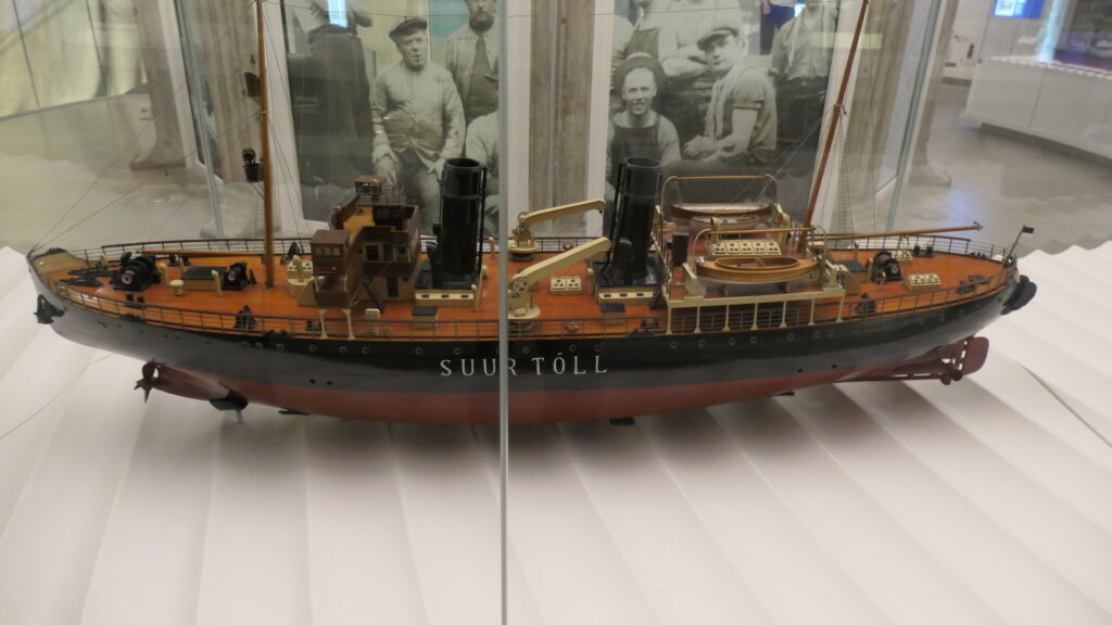 Ein Modell der Suur Tóll, dahinter ein schwarzweiß Foto mit Besatzungsmitgliedern